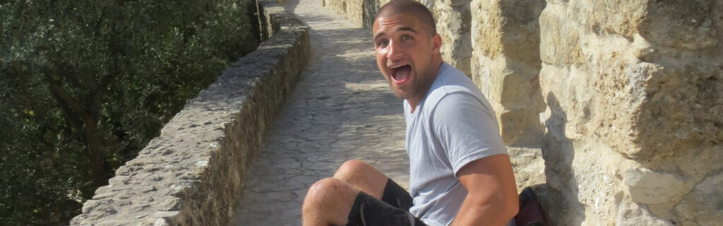 Young man on a stone walkway looks excited