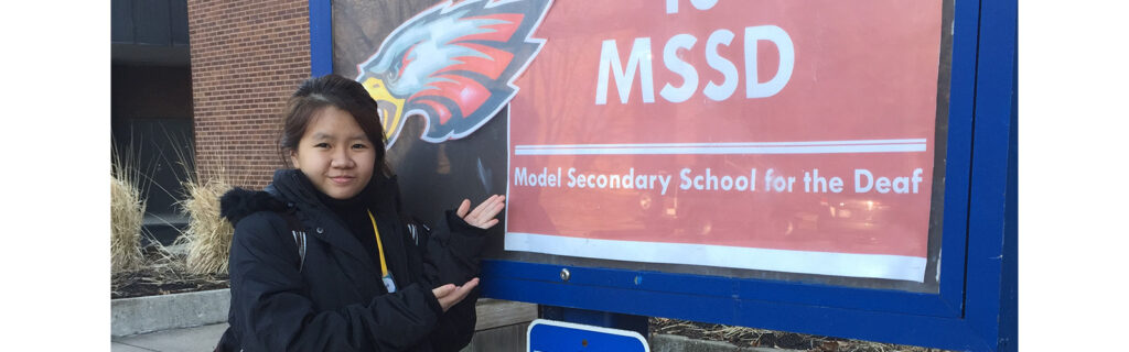 Deaf female student from Malaysia stands in front of the Model Secondary School for the Deaf