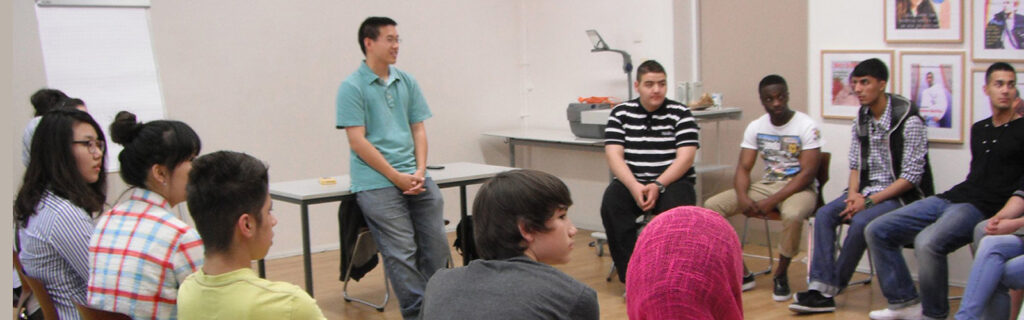 An ESL class sits in a circle with the teacher at front.