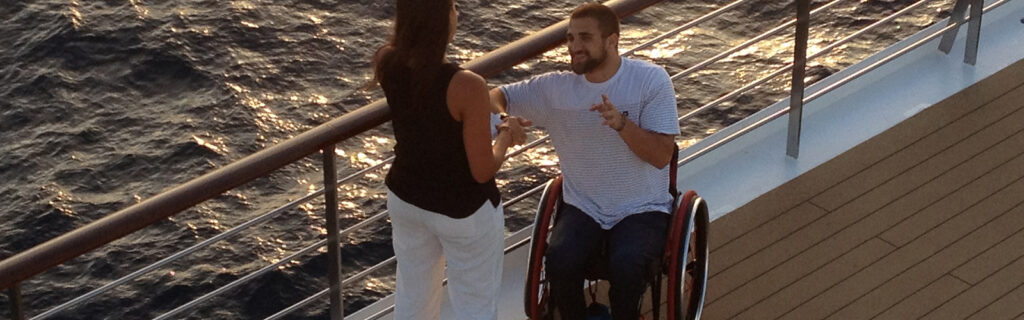 Jake Robinson in his wheelchair talking with student on the ships deck