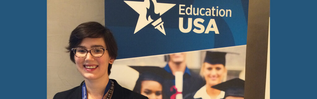 Molly Roza stands in front of an EducationUSA banner.