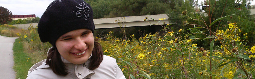 Student smiling in a field of flowers.