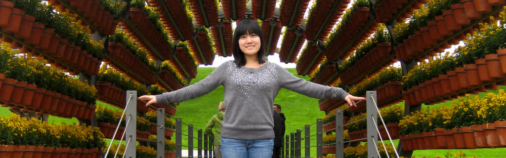 Asian-American youth stands under potted plants in Germany