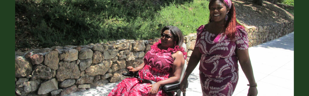 An African woman with a disability and her personal assistant walking.