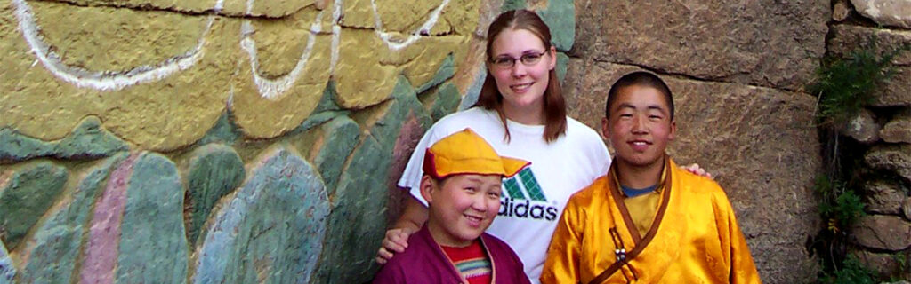 Melissa and young monks in front of mural