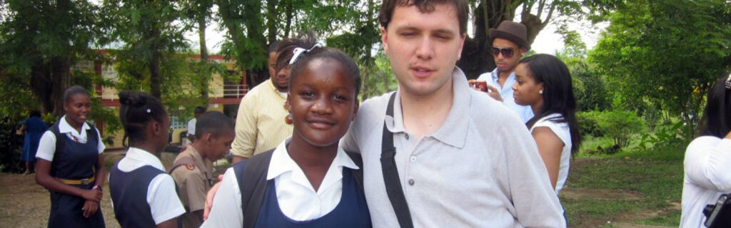 A young American man with autism poses with a Jamaican school girl.