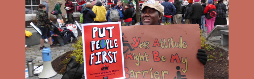 Protest signs say Put People First. Your Attitude May be My Barrier