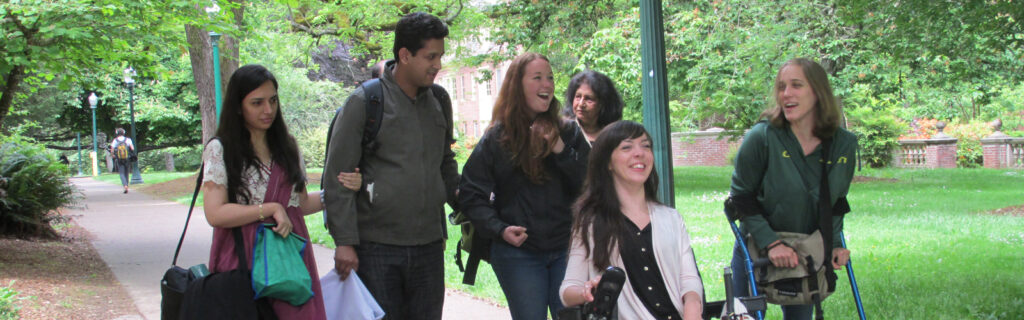 A group of young Americans and exchange students with and without disabilities talk while walking through a college campus.