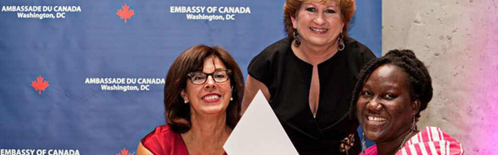 Two women present a third women with a special award certificate.