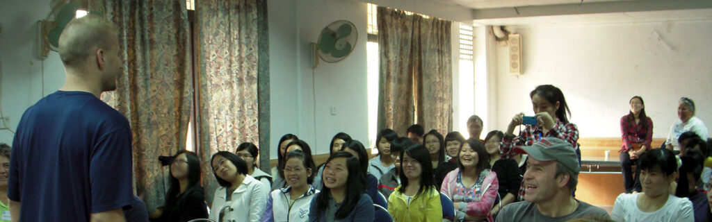 A caucasian American man talks to a classroom of Chinese female students.