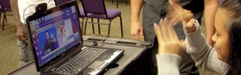 A girl is seated at a computer and having a conversation via video relay.