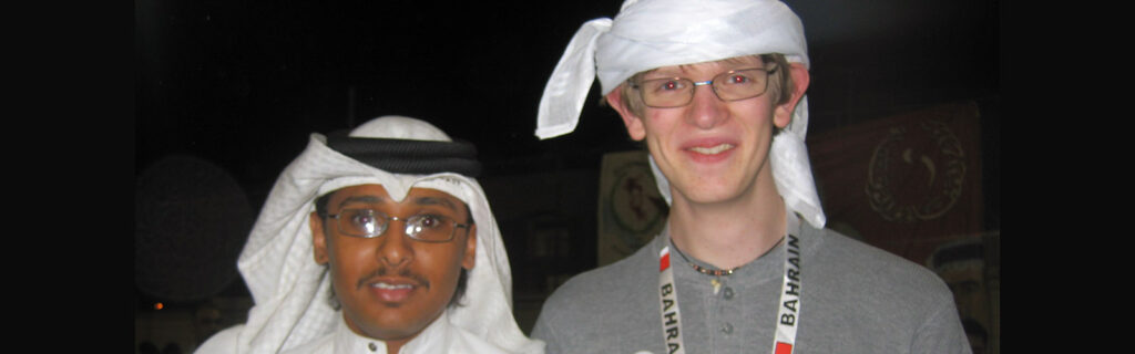 A Bahraini man in cultural dress stands with an American man.