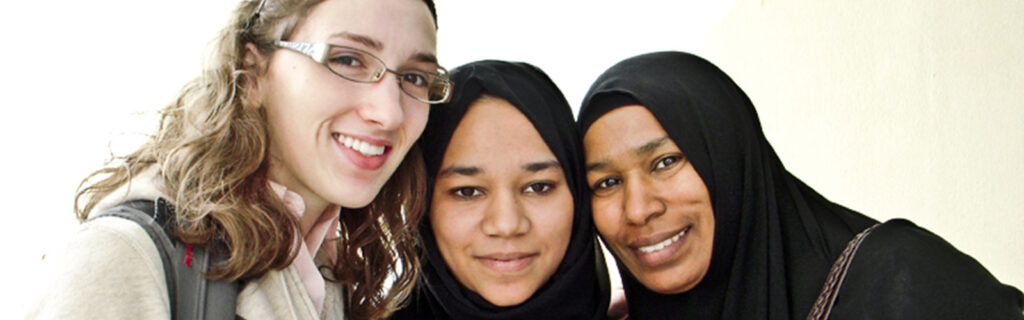 Young American with learning disability smiles with two Muslim women during a cultural exchange