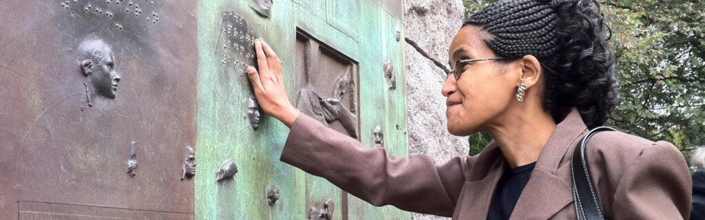 African exchange participant touching a tactile wall while visiting FDR Memorial in Washington DC