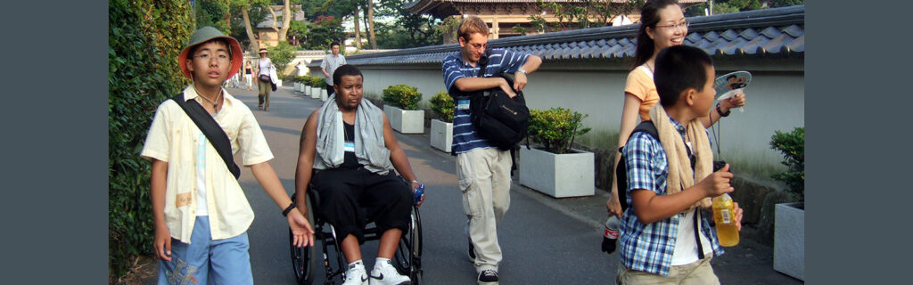 African American man in a manual wheelchair strolls along with others in Japan