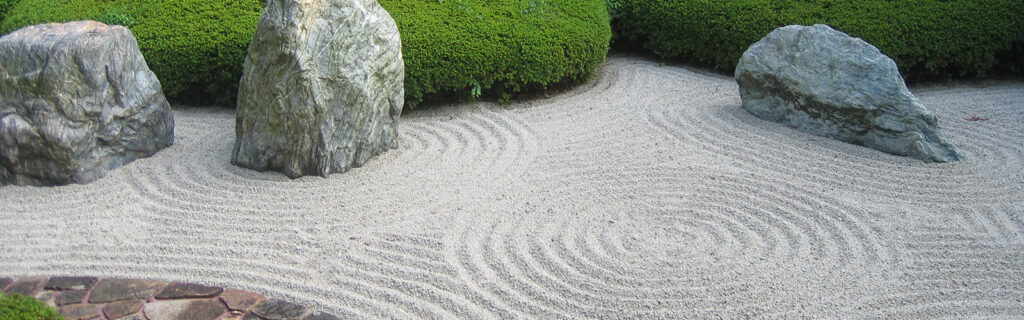 Rocks and sand are positioned in a zen garden.