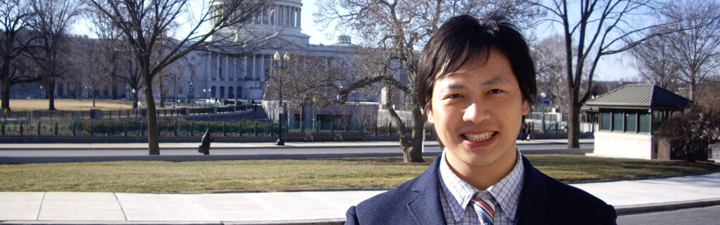 Well Zhao stands before the Capitol building and cherry trees in D.C.