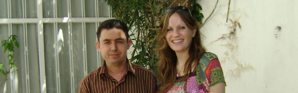 Image of a man and a woman standing outdoors in front of a window.