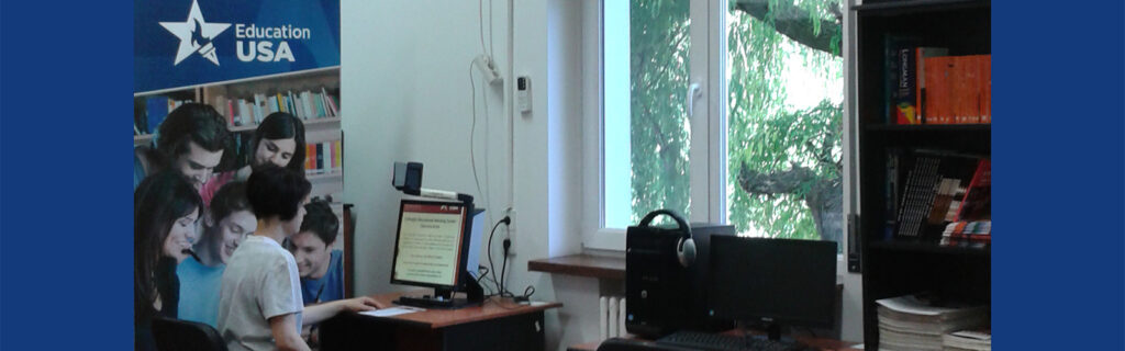 Ruxandra Radulescu sits at computer with EducationUSA banner behind