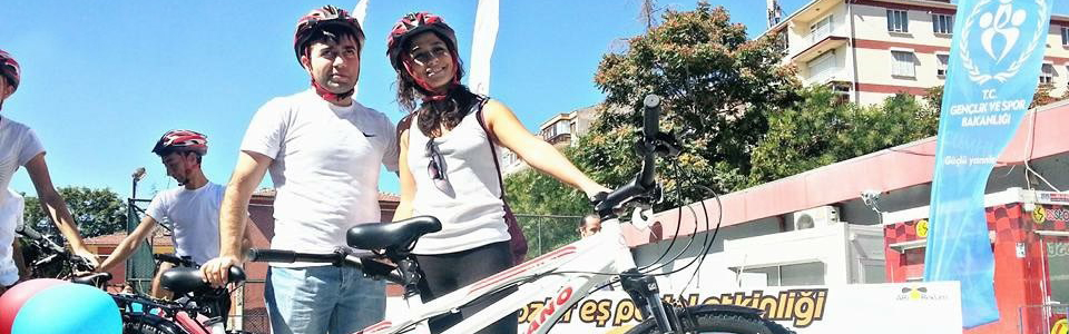 Two young adults, male and female stand behind a tandem bicycle