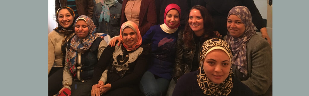 Reem sitting and smiling with students from the Association of the Visually Impaired in Alexandria, Egypt.