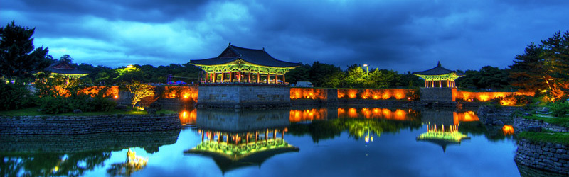 Lights of a pagoda are reflected by a pond at dusk