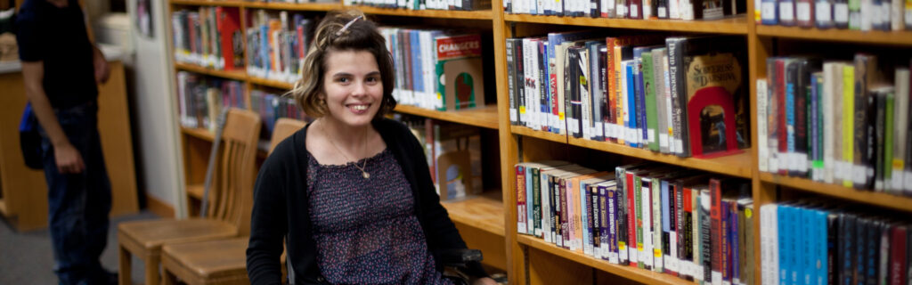 Ana smiling in front of bookshelves at school library