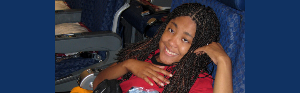 Young woman seated very low in her airline seat smiles