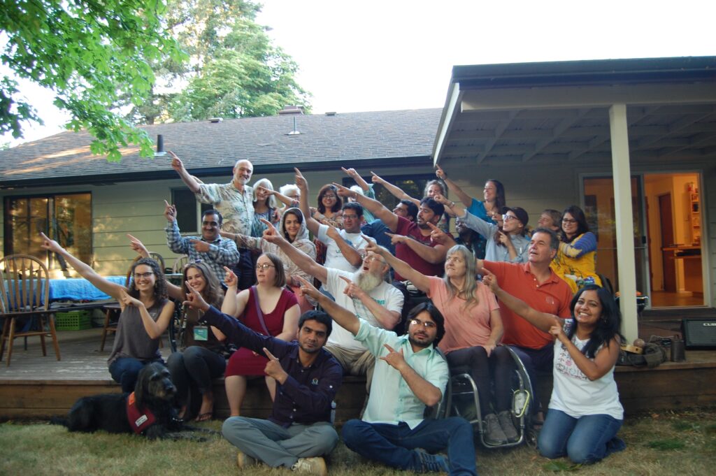 Group photo with delegates, MIUSA staff and Eugene community members all pointing up to their right.