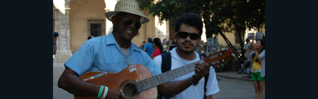 Chris standing next to a man playing a guitar in an open market