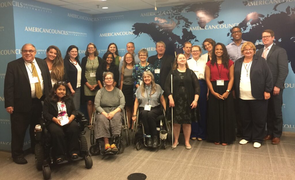 21 RTC members smile and pose together in front of wall designed with a world map.