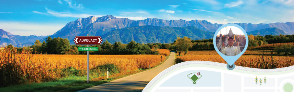 In the foreground graphic, a metal pole supports a brown road sign labeled “Advocacy” and below it, a green sign labeled “Univ Illinois Urbana-Champaign.” In the background photo, a straight road passes through shadows to bright sun as it leads to golden grass, green trees, and blue mountains beyond. A map marker shows Hugo Trevino in front of a Buddha statue