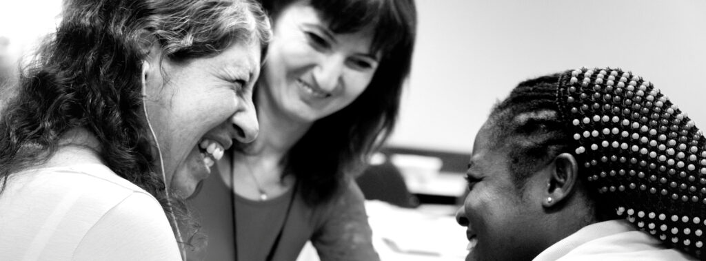 Black and white photo of three women smiling and speaking closely