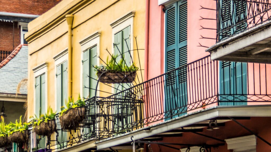 New Orleans buildings painted in pastel pinks and yellows with balconies adorned with plants