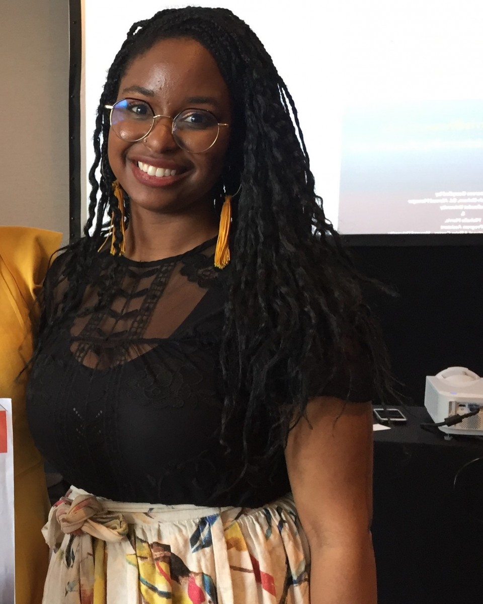 Michelle stands in front of a screen and projector smiling at camera