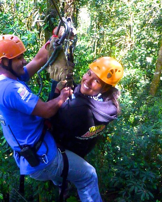 Juanita being secured in ziplining harness, smiling at camera