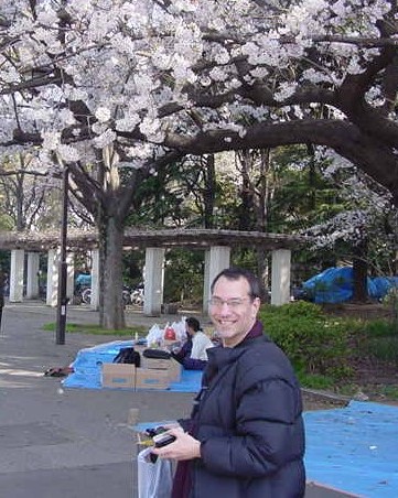 Kenny beneath cherry blossom tree wearing winter coat