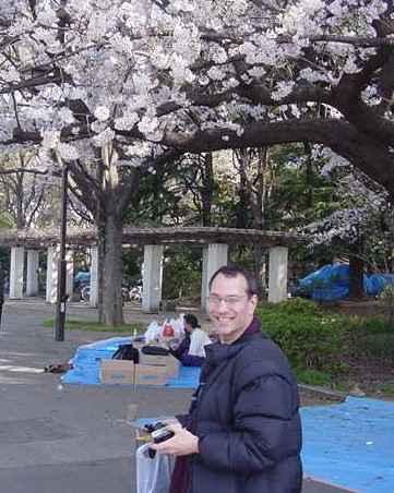 Kenny beneath cherry blossom tree wearing winter coat