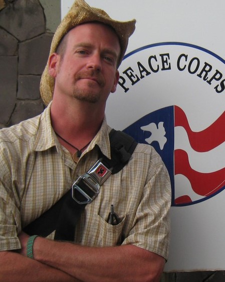 Allen wearing cowboy hat in front of Peace Corps sign