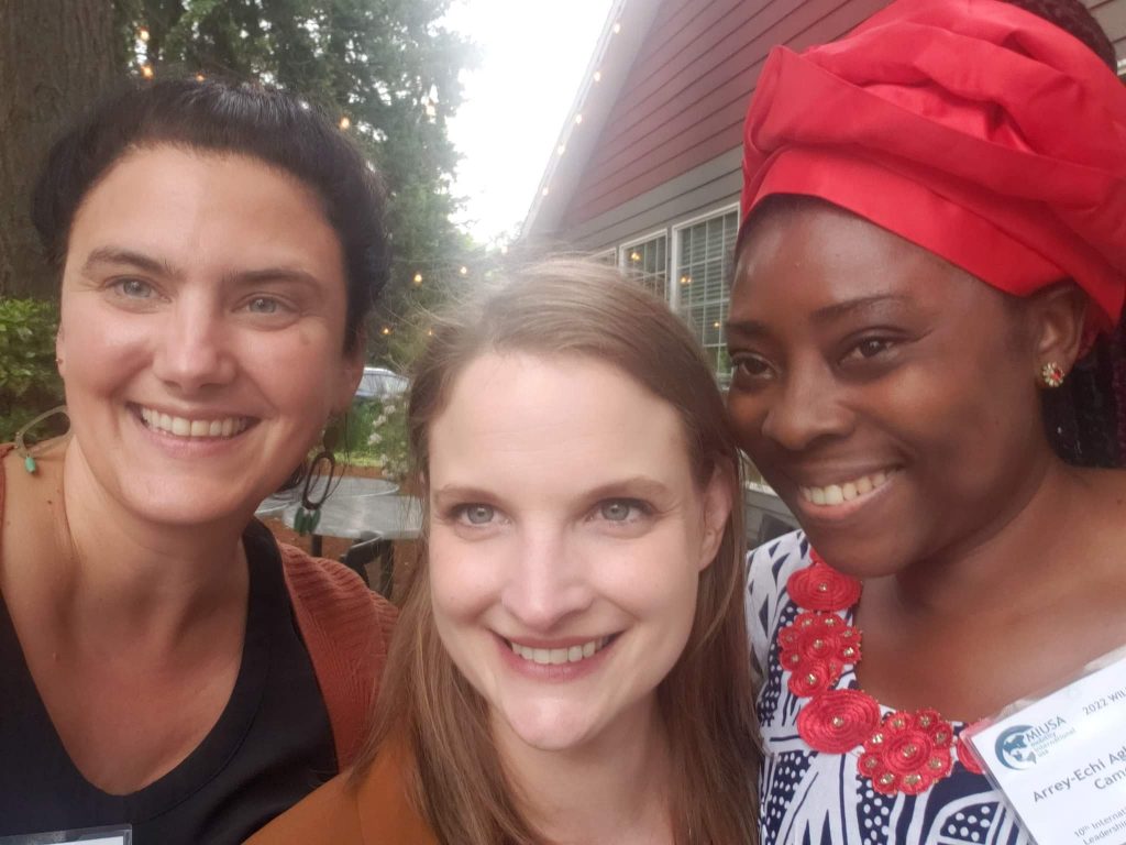 Close up of three women, two from the U.S. and one from Cameroon, smiling together facing the camera. 