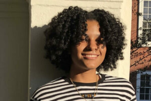 Portrait of Bobbi with black curly afro and a black/white striped shirt. 